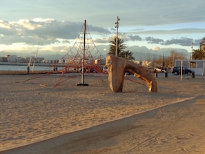 A sandy beach with a large sculpture and a tall structure in the background. - I villa with private pool, large garden, porch, terrace and playground. (Roses)