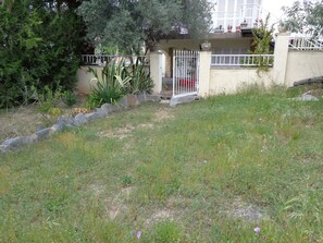 A residential area with a gated entrance, a small garden with various plants, and a building with a balcony. - I villa with private pool, large garden, porch, terrace and playground. (Roses)
