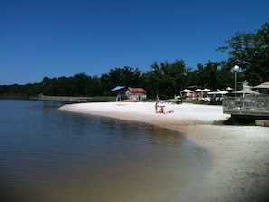 Une plage avec une petite maison et des parasols.