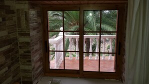 Ein Zimmer mit Blick auf einen Balkon mit weißen Brüstungen und Palmen.