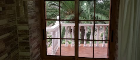 Una habitación con vista a un balcón de balaustradas blancas y palmeras.