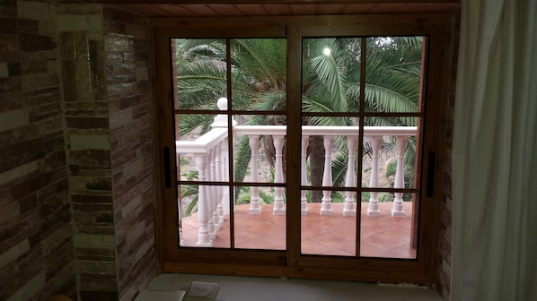 A room with a view of a balcony with white balustrades and palm trees.