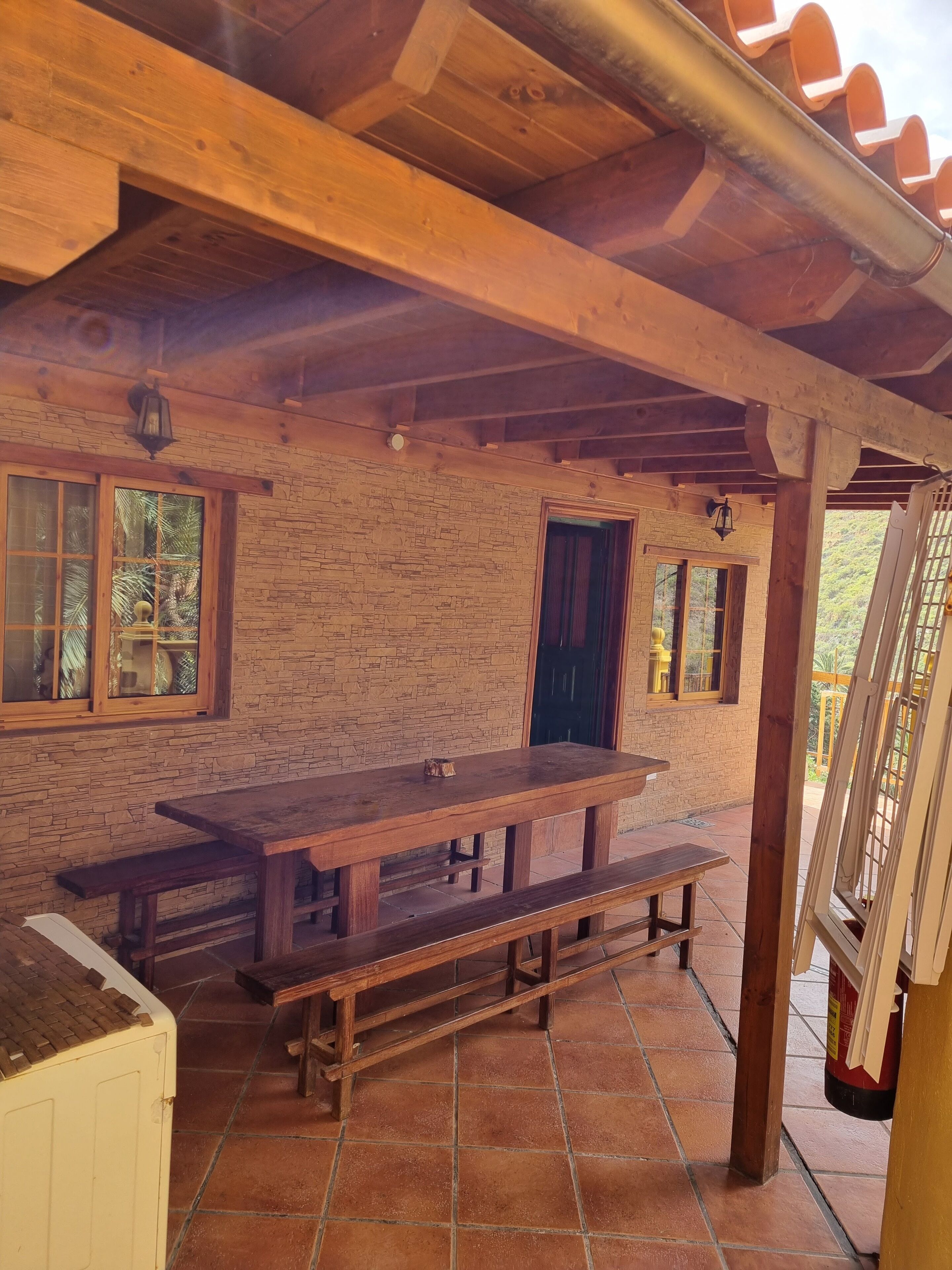 A rustic wooden cabin with a stone wall, a wooden bench, and a tiled floor.