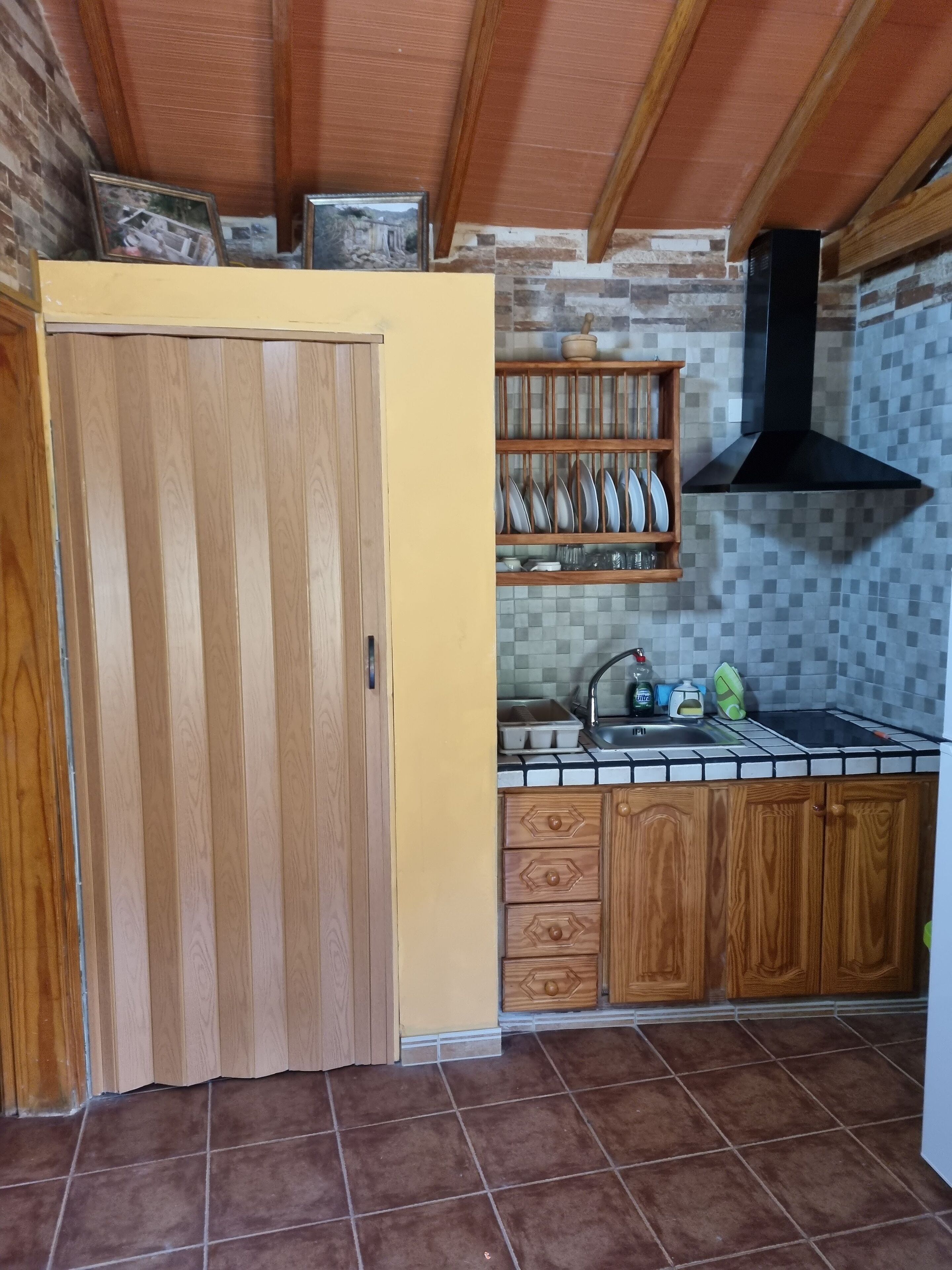 A kitchen with wooden cabinets, a tiled backsplash, and a black range hood.