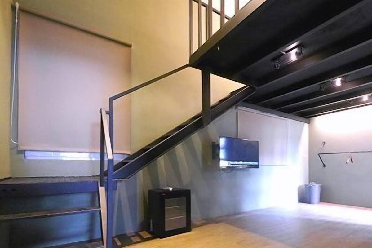 A staircase with a metal railing leading to a landing. A television is mounted on the wall above the landing.