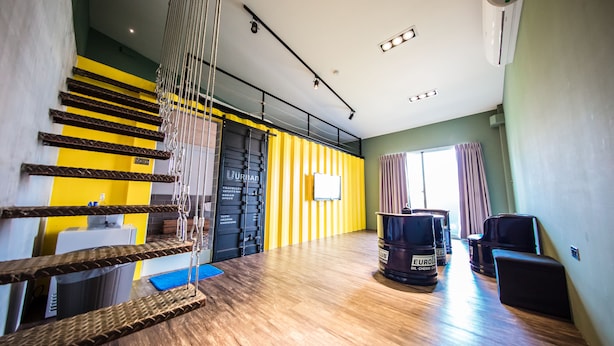 A spacious room with a wooden floor, a yellow and black striped wall, a large window with curtains, and a black chair. - Urban (Kaohsiung)