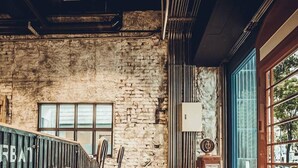 A rustic interior with exposed brick walls, a wooden staircase, and large windows. - Urban (Kaohsiung)