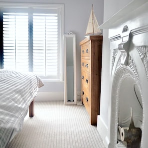 A bedroom with a bed, a dresser, and a window with blinds.