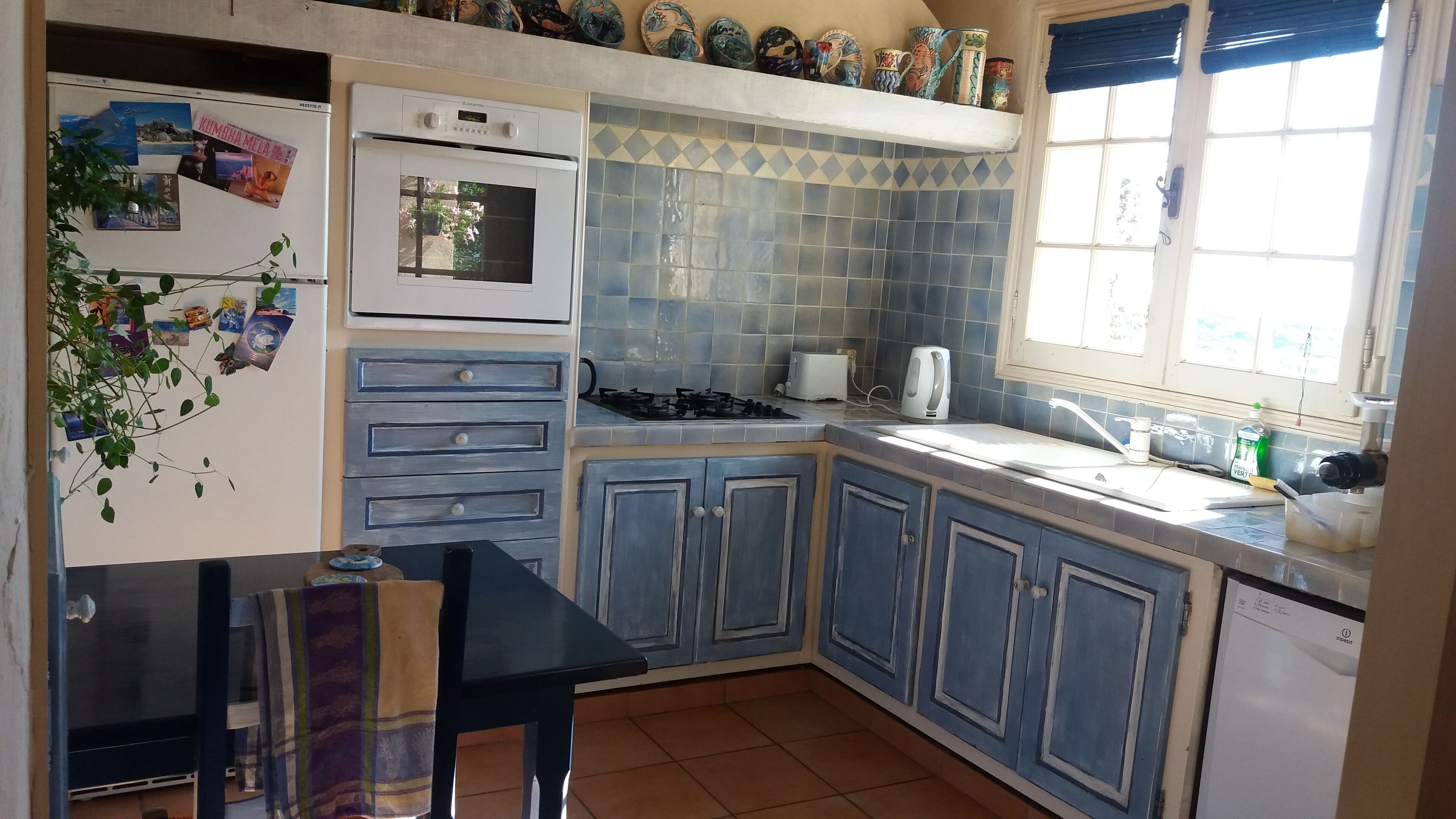 A compact kitchen with a gas stove, oven, and a window with curtains.