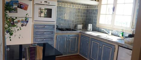 A compact kitchen with a gas stove, oven, and a window with curtains.