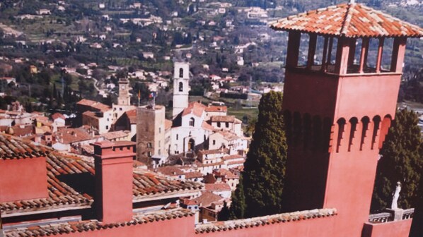 Una població històrica amb edificis destacats amb teulades vermelles, una torre campanar i una torre d'arcs.