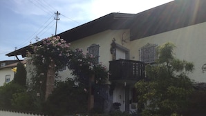 Une maison avec un balcon, un portail décoratif et un arbre aux fleurs roses.