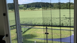 Una habitación con un ventanal grande que ofrece vistas a un campo verde y árboles.