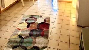 A hallway with a patterned rug, a white chair, a peacock painting, and a view into a room with a pool. - Apartment in the romantic garden<br>Note days of action !!!  (Amelinghausen)