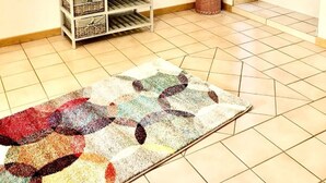 A room with a tiled floor, a bench with baskets, a colorful rug, and a window with curtains. - Apartment in the romantic garden<br>Note days of action !!!  (Amelinghausen)