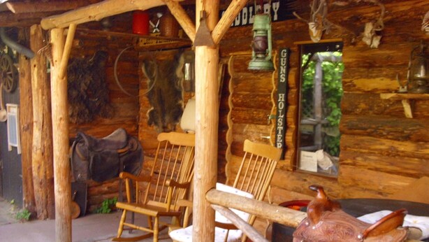 A rustic wooden cabin with a porch, rocking chairs, and a mounted animal head. - Apartment in the romantic garden<br>Note days of action !!!  (Amelinghausen)