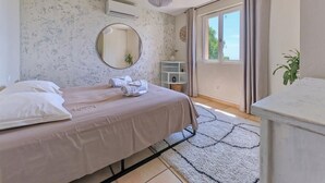 A bedroom with a bed, a round mirror, a window with curtains, and a plant. - Spacious air-conditioned villa, heated pool and SPA, breathtaking views. (Grasse)