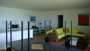 Un espace de vie compact comprenant un coin repas, une kitchenette et un canapé avec des coussins.