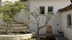 A courtyard with a white building, a tree, and a small garden area. - Architect-designed house with swimming pool, near the sea, 6 adults / 2 children (Draguignan)
