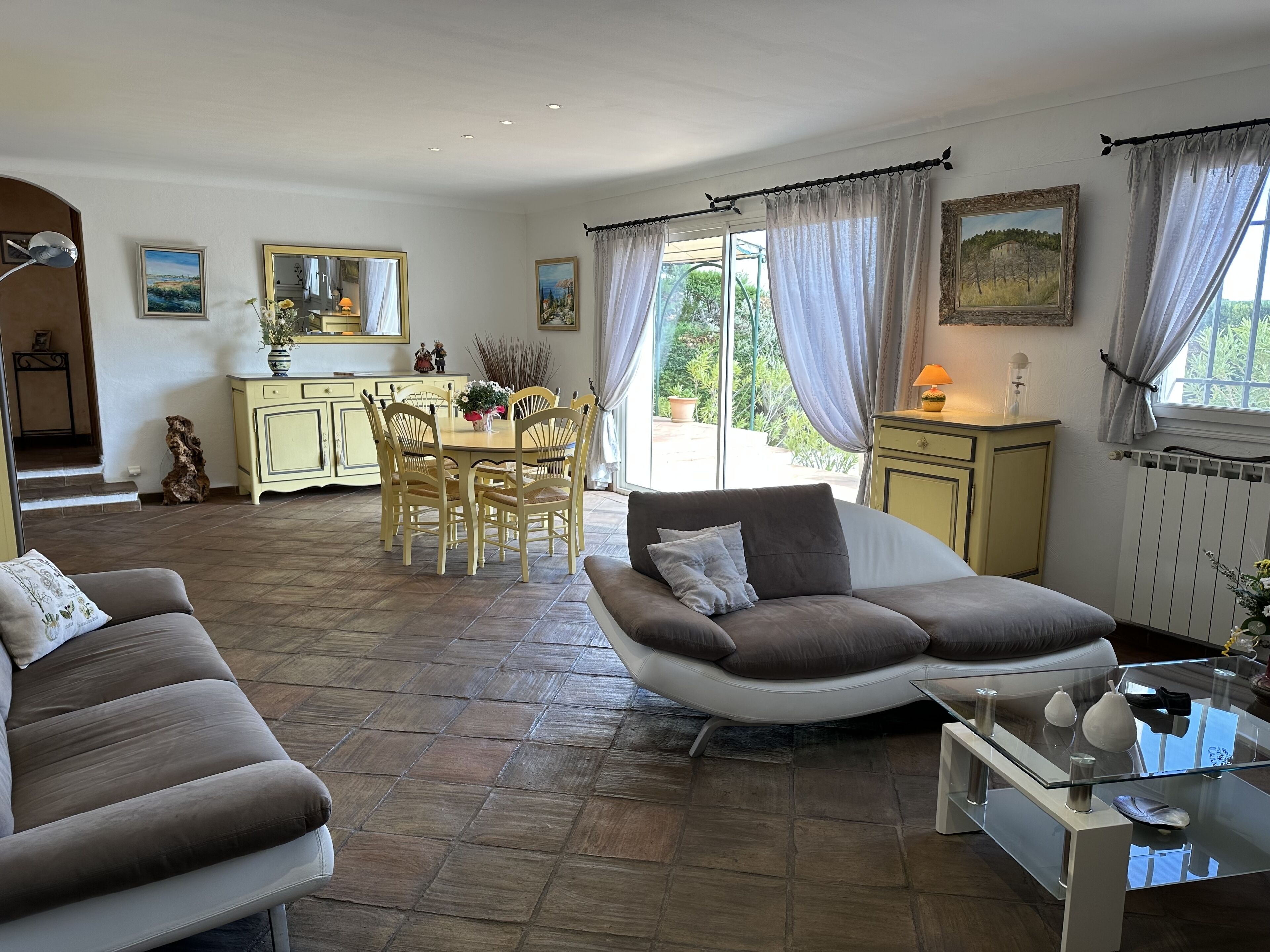 Un salon spacieux comprenant un canapé, une table basse en verre et un coin repas avec une table et des chaises.