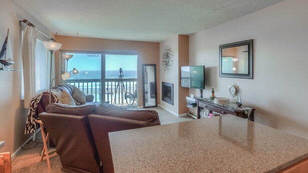 A cozy living room with a large window, a sofa, a TV, and a small table.