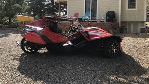 Ein rotes Motorrad vor einem Haus mit einer Ziegelwand und einem Fenster.
