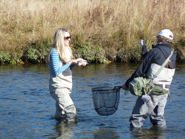 Two people standing in a river, one holding a net.