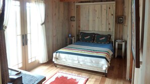 Ein Schlafzimmer mit Holzwänden, einem Bett, einem Schreibtisch und einem Stuhl.