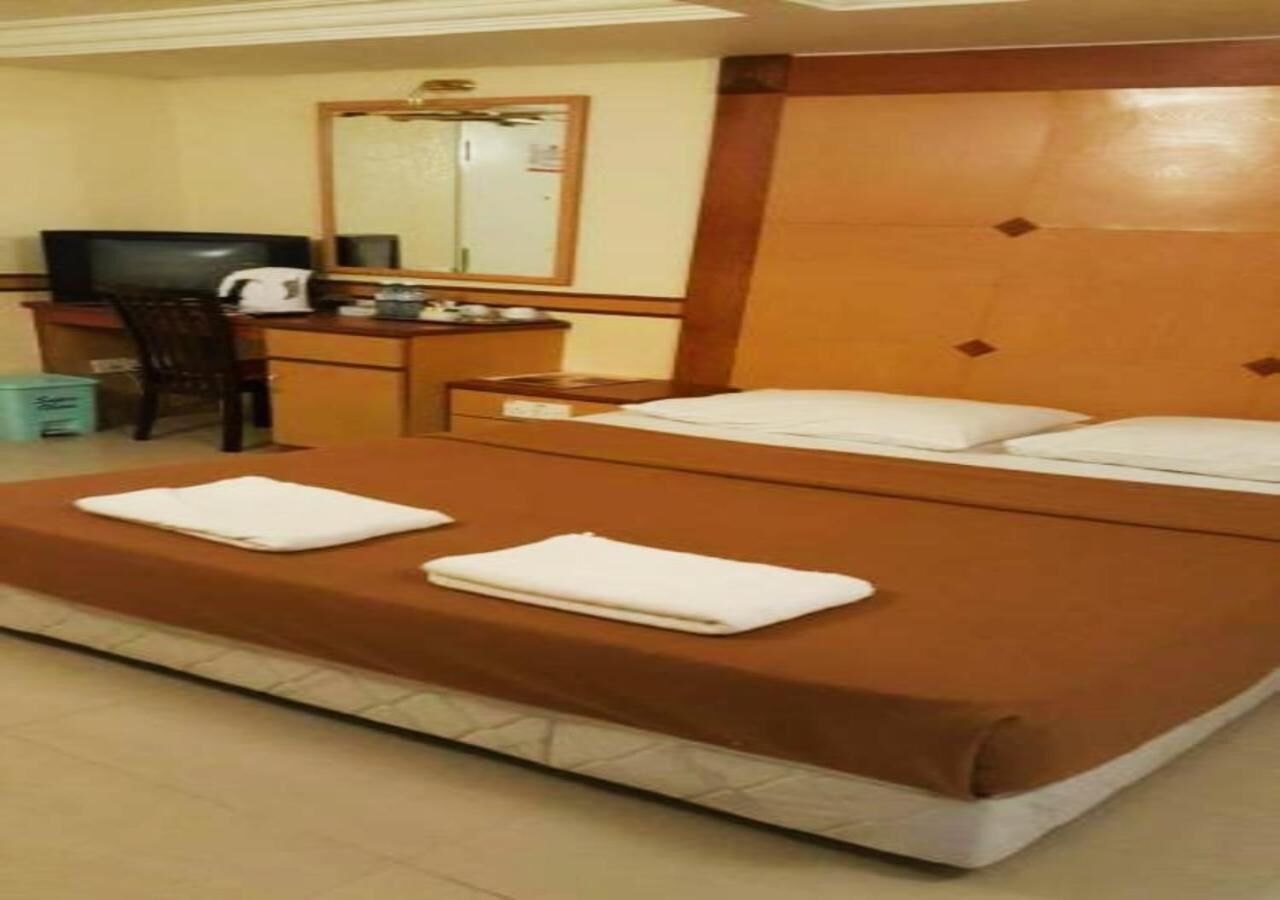 Una habitación de hotel con una cama, un escritorio, una silla, un televisor y un espejo.
