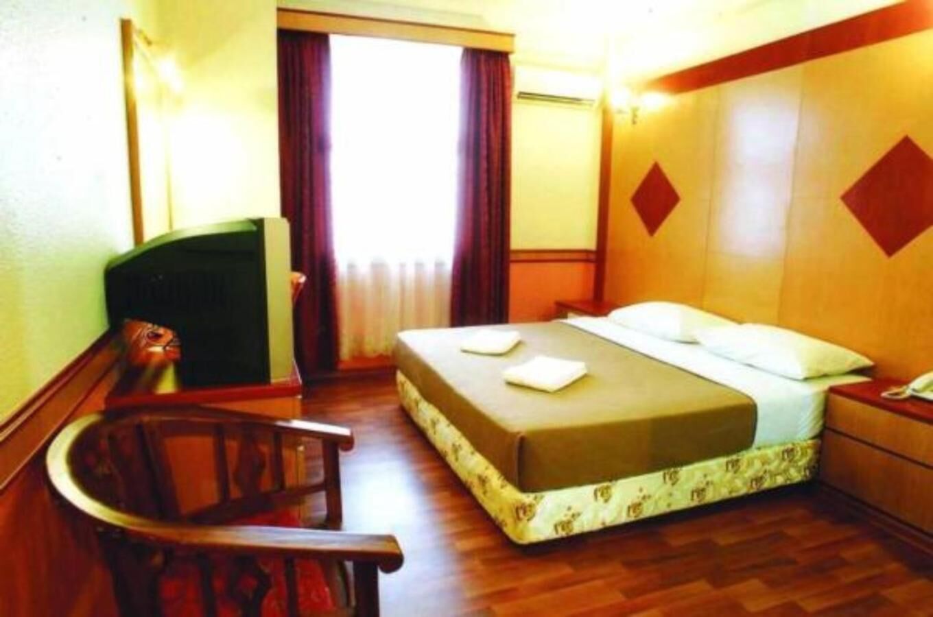 A hotel room with a bed, a desk, a chair, and a television.