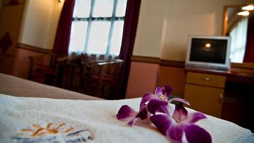 A hotel room with a bed, a TV, and a window with curtains.
