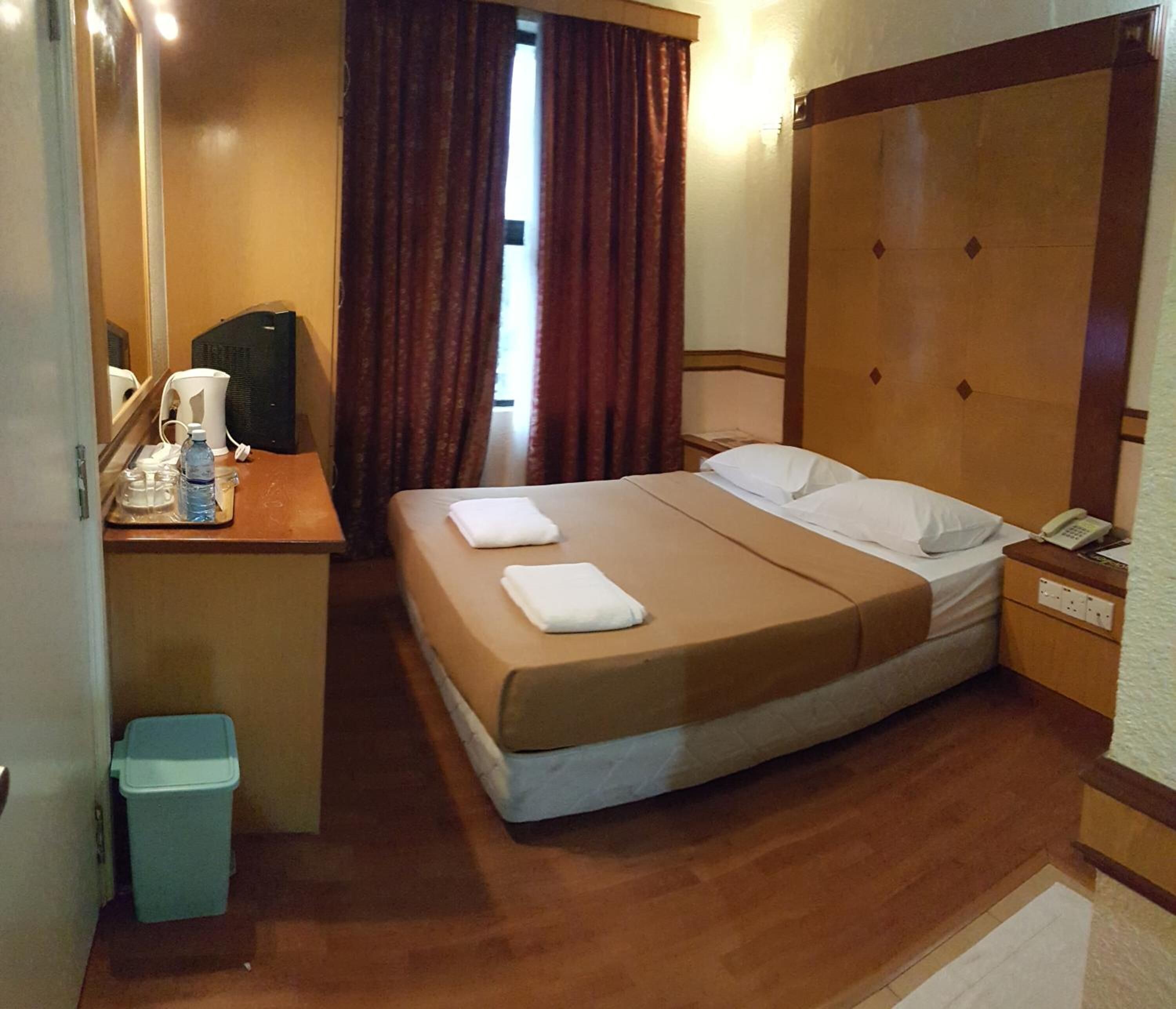 Une chambre d’hôtel avec un lit, une table de chevet et une poubelle.