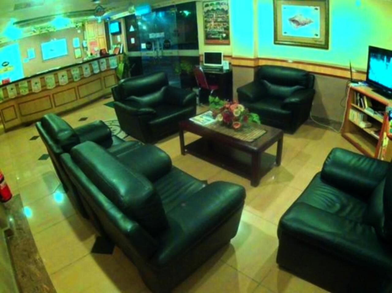 A lobby with leather sofas, a coffee table, and a TV on a stand.