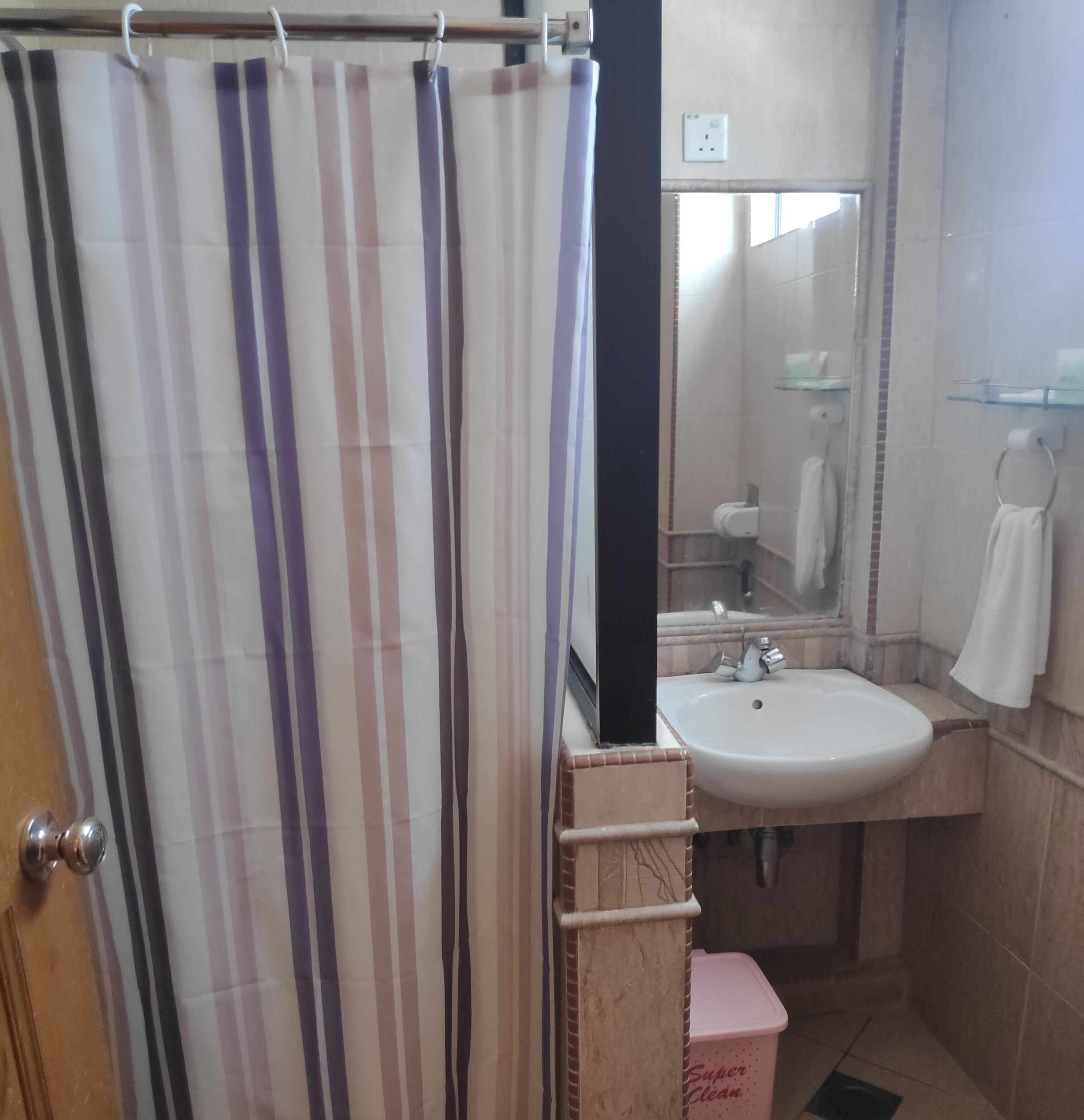 Un baño con cortina de ducha a rayas, un lavabo, un espejo y un perchero para toallas.
