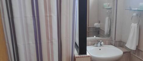 Un baño con cortina de ducha a rayas, un lavabo, un espejo y un perchero para toallas.