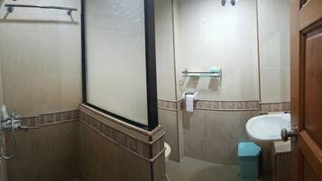 Un baño con ducha, lavamanos y estante de vidrio.