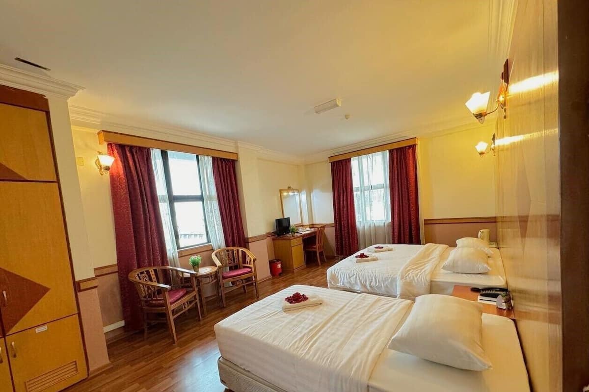 Quarto de hotel com duas camas, uma escrivaninha, uma cadeira e um guarda-roupa.