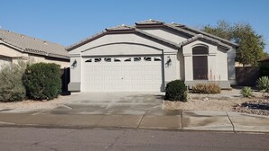 A single-story house with a garage, a small front yard, and a clear blue sky. - Beautiful Desert Vacation Home.  Heated Pool! Close to Stadium & Wigwam Resort (Litchfield Park)