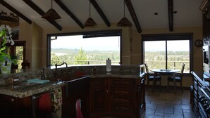 A kitchen with a large island, wooden cabinets, and a view through large windows.