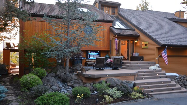 A wooden house with a patio, outdoor seating, and a small dog.