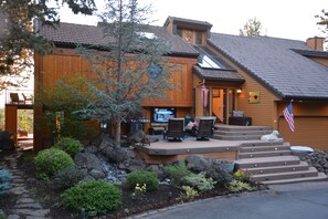 A wooden house with a patio, outdoor seating, and a small dog.