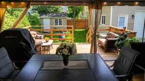An outdoor patio with a dining table, chairs, and a grill.