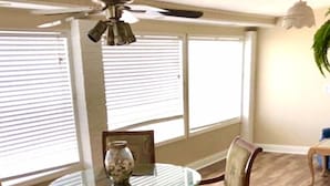 A dining area with a round table, four chairs, and a ceiling fan.