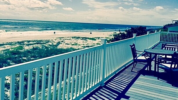 A wooden deck with a railing overlooking a beach.