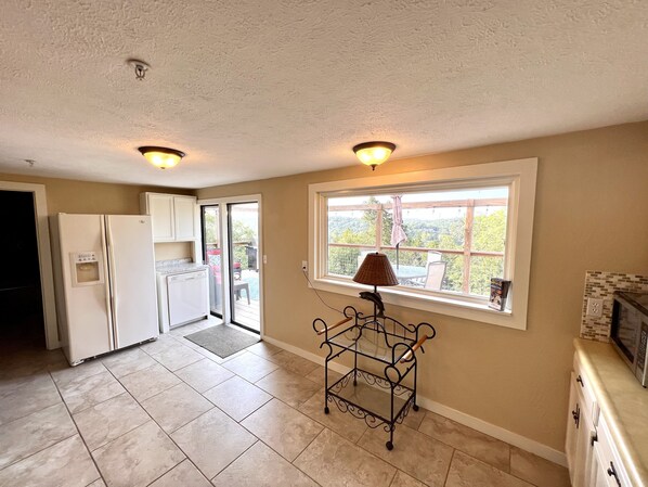 A kitchen with a refrigerator, dishwasher, and a window with a view of greenery.