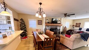 Una sala de estar acogedora con chimenea, un comedor con mantel a cuadros y un árbol de Navidad.