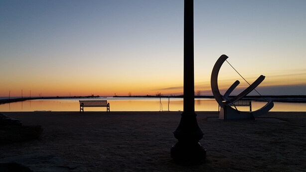 Une plage avec un banc et une sculpture.
