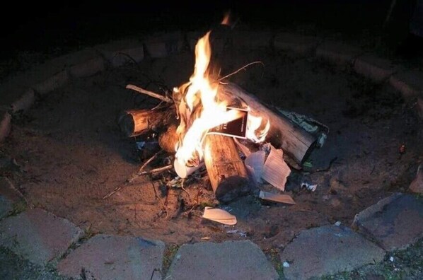 A campfire with logs and a book, surrounded by a stone fire pit.