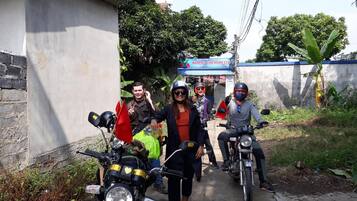 A group of people on motorcycles parked on a narrow street with a building in the background.