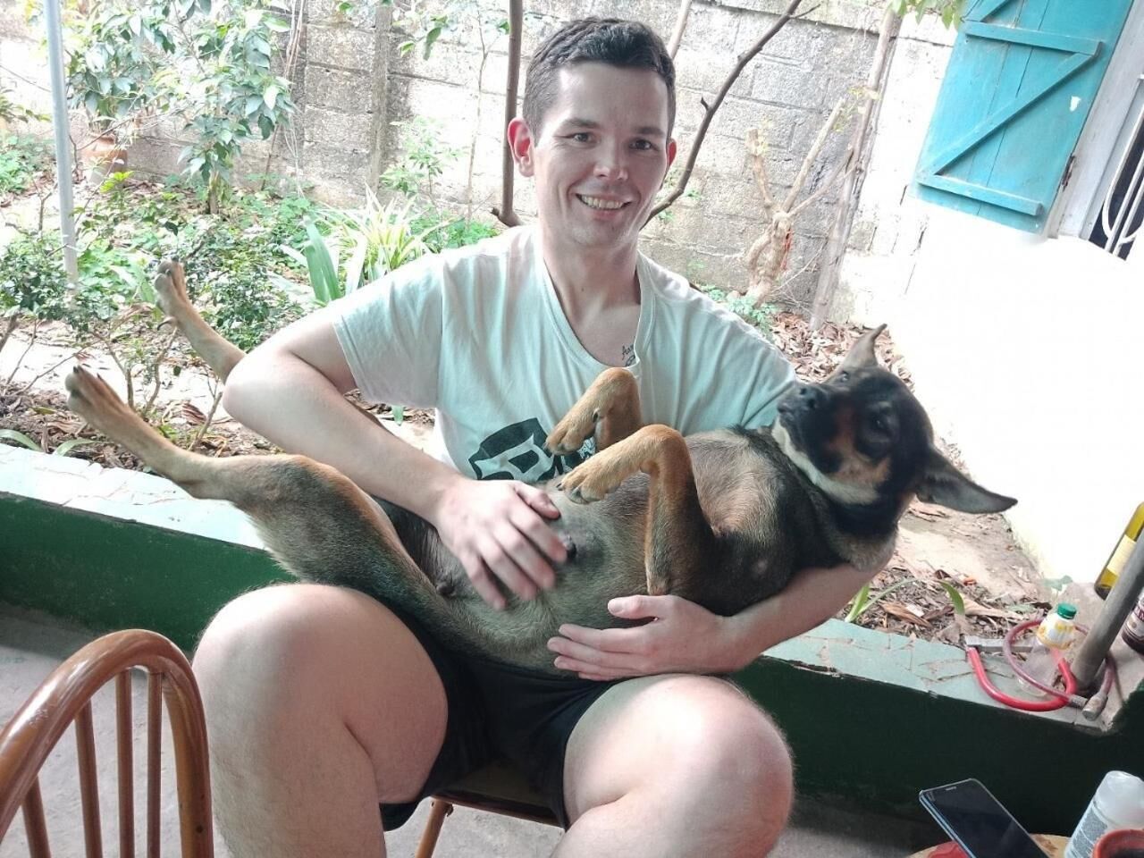 A person sitting on a chair holding a large dog.